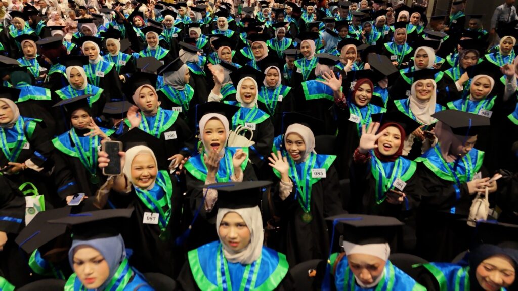 Wisudawati IIQ Jakarta mengenakan toga dan melambaikan tangan pada wisuda ke-27
